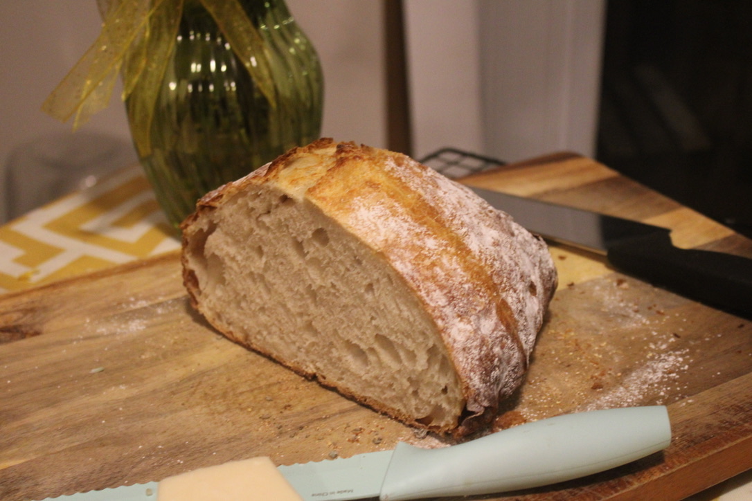 a sliced loaf of sourdough, on a wooden cutting board